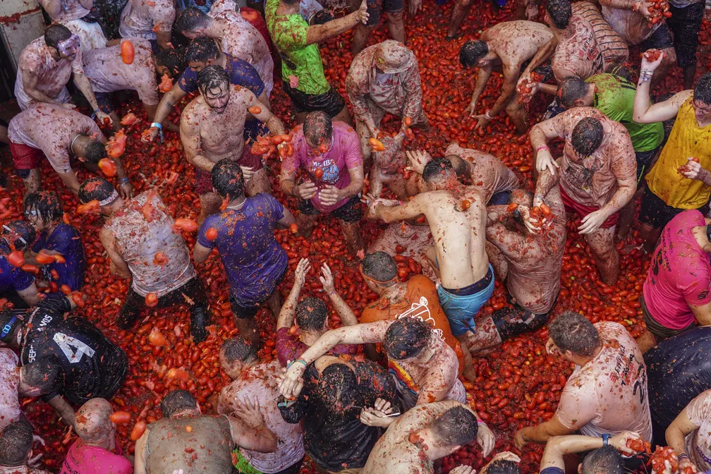 Participantes jogam tomates uns nos outros durante o festival "Tomatina" em Buñol, na Espanha, em 31 de agosto de 2022 - Foto: Alberto Saiz/AP