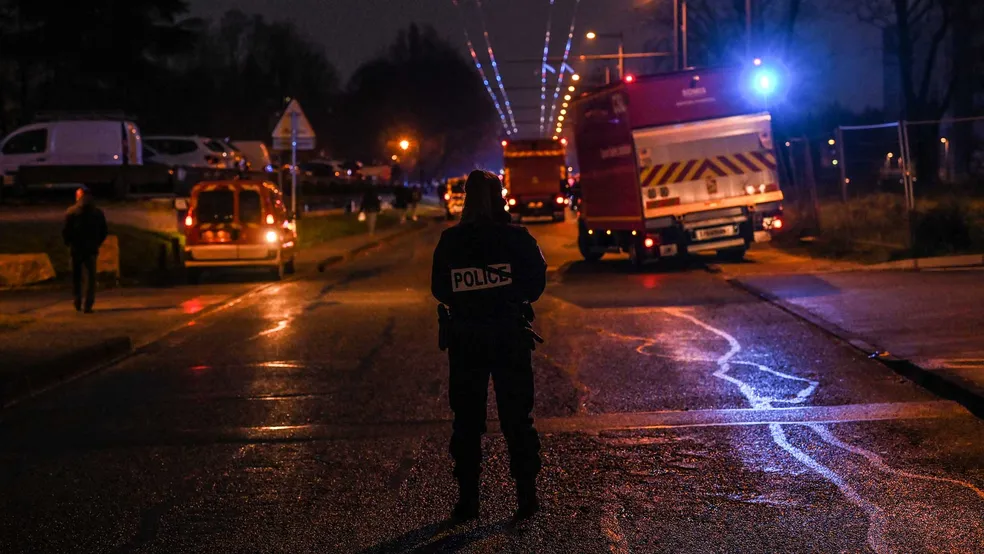 Policiais guardam um perímetro de segurança enquanto bombeiros e equipes de resgate trabalham em um prédio atingido por um incêndio em Vaulx-en-Velin, na França - Foto: OLIVIER CHASSIGNOLE / AFP PHOTO