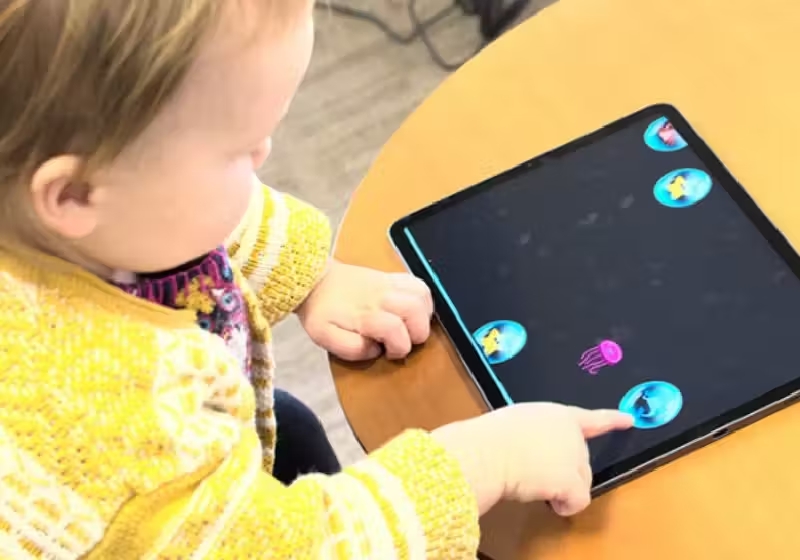 Criança no jogo de estourar bolhas que faz parte do aplicativo para tablet que pode ajudar a identificar autismo com 87% de precisão. - Foto: reprodução / Duke University