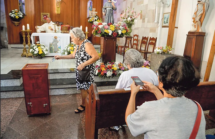 Tradicionais folhetos usados para os fiéis acompanharem a missa podem ser baixados através do celular  Foto: Agência O Globo